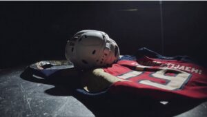 An empty Florida Panthers hockey bench with a jersey and stick symbolizing Matthew Tkachuk’s absence during the NHL season.