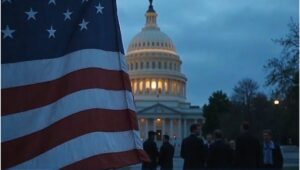 An editorial illustration of the U.S. Capitol at dusk with lawmakers in heated discussion, an American flag in the foreground, and National Guard presence in the background, symbolizing the tense political climate of 2025.